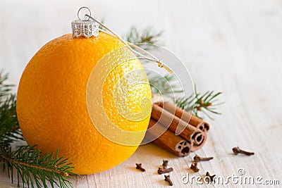 Abstract orange christmas ball, with cinnamon, cloves and christmas tree in background Stock Photo