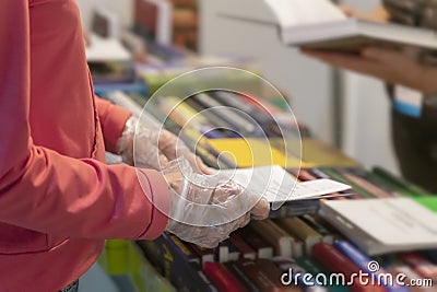 Abstract person in disposable protective gloves with book in hands, library, bookstore. New normal. Risk area for spreading Stock Photo