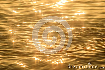 Abstract photo of surface water of sea or ocean at sunset time with golden light tone. Stock Photo