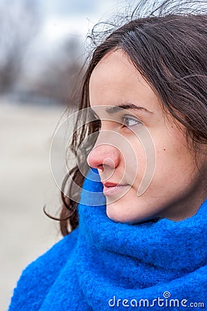 Abstract portrait of young beautiful girl with sad and adorable eyes with sensitive look in the cold day and blue scarf extremely Stock Photo