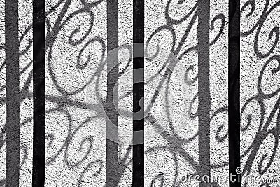 Abstract shadows of a curved wrought iron door on a wall, black and white Stock Photo