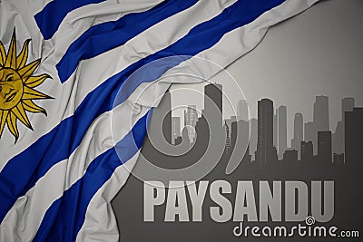 Abstract silhouette of the city with text Paysandu near waving national flag of uruguay on a gray background Stock Photo