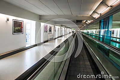 Abstract stylized perspective blur of moving sidewalk in airport with unrecognizable passenger with luggage cart Stock Photo