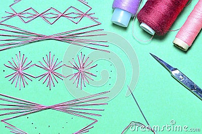 Abstract symmetrical patterns sewn on paper using cotton thread. Coils of thread, scissors and needle. Stock Photo