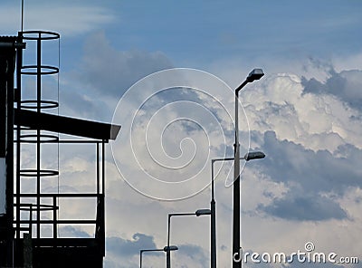 Clouds and blue sky on spring day with steel platform and street lamps Stock Photo