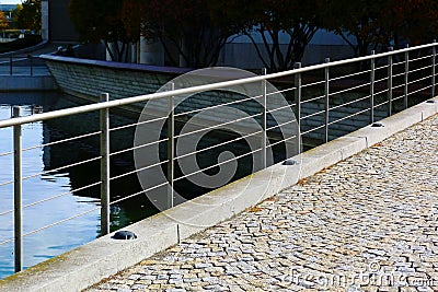 Abstract view of modern stainless steel wire guard rail along pond Stock Photo