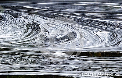 Abstract white foam swirls on dark water Stock Photo