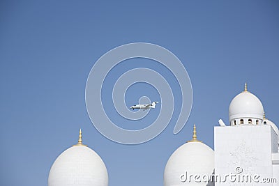 Abu- Dhabi UAE -March 03 2013:private jet flies over the domes of Sheikh Zayed Mosque Abu Dhabi UAE Stock Photo