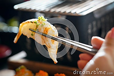 Aburi Engawa Sushi is clamped with metal chopsticks Stock Photo