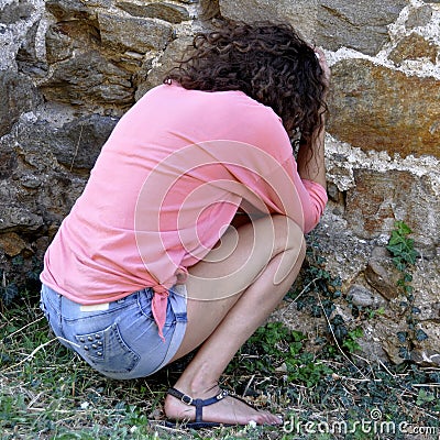 Abused and frightened woman sitting in the corner of a derelict Stock Photo