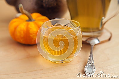 acacia honey in a crystal vase, a silver teaspoon, a ceramic teapot and a small decorative pumpkin Stock Photo