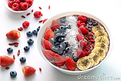 Acai Berry superfoods smoothies white bowl with chia seeds, strawberry, goji berry, coconut, blueberry, raspberry toppings Stock Photo