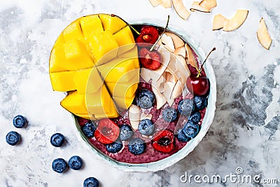 Acai breakfast superfoods smoothie bowl with mango, blueberry, cherry, coconut flakes. Overhead, top view Stock Photo