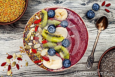 Acai breakfast superfoods smoothies bowl with chia seeds, bee pollen, goji berry toppings and fruits. Overhead. top view, flat lay Stock Photo