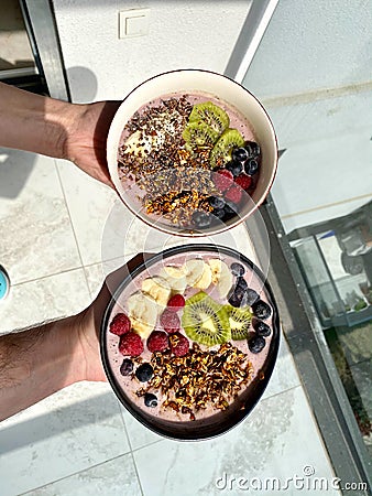 Acai Smoothie Bowl with Baked Granola, Blueberries, Raspberry, Banana and Kiwi in Hand Stock Photo