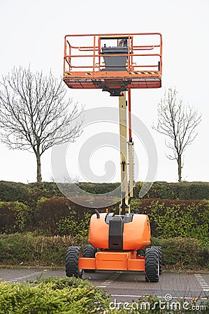 Access platform equipment powered high in sky in orange for high working platform height safety at construction building Stock Photo