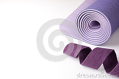 Accessories for yoga, pilates or fitness. Purple yoga mat and purple belt on a white background with copyspace Stock Photo