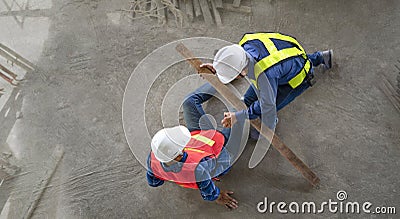 accident in site work,a piece of wood fell from height hit on a worker's legs while working at a new building Stock Photo