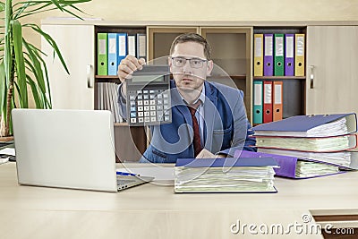 Accountant businessman at his desk in the office holds out forward a calculator. Financial check. Preparation of a report by an Stock Photo