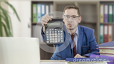 Accountant businessman at his desk in the office holds out forward a calculator. Financial check. Preparation of a report by an Stock Photo