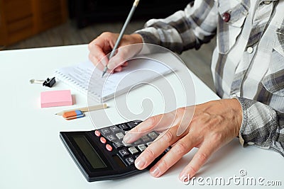 The accountant calculates. On the table business objects, calculator, stapler, hole punch, paper clips, buttons, and other office Stock Photo