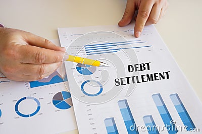 Accountant shows to the sign DEBT SETTLEMENT sign on the financial document Stock Photo