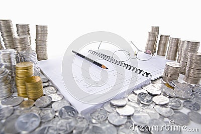 Accounting ledger between piles of coins Stock Photo