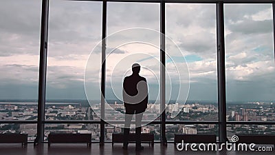 Achtermening van de mens in formele reeksen die zich voor panoramisch venster met stadsmening bevinden een mens bevindt zich voor stock video Achtermening van de mens in formele reeksen die zich voor panoramisch venster met stadsmening bevinden een mens bevindt zich voor stock video