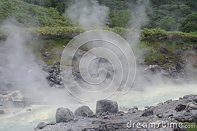 Acidic hot spring stream water with hydrochloric acid emitting steam in mountain valley at Tamagawa Onsen Hot spring in Japan Stock Photo