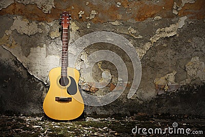 Acoustic guitar against grungy wall Stock Photo