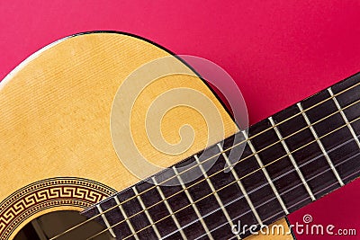 Acoustic guitar close-up on a pink background. Music hobby concept. Stock Photo