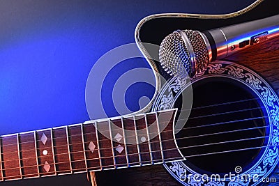 Acoustic guitar and microphone isolated with red and blue lights Stock Photo