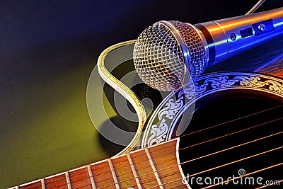 Acoustic guitar and microphone isolated with yellow and blue lights Stock Photo