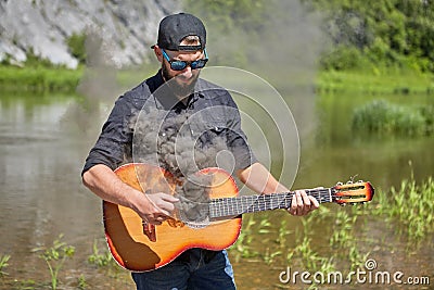 The guitarist uses a smoking guitar in nature Stock Photo