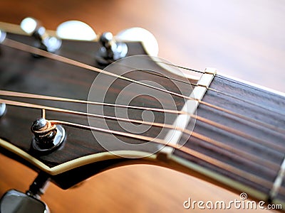 Acoustic wood guitar close up on wooden background with fretboard, strings, and tuners for music blogs, website banners. Stock Photo