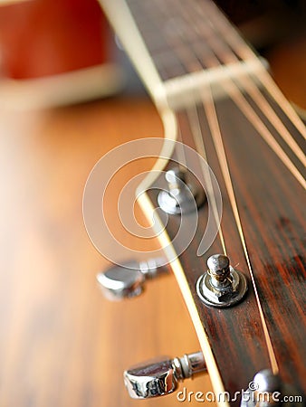 Acoustic wood guitar close up on wooden background with fretboard, strings, and tuners for music blogs, website banners. Stock Photo