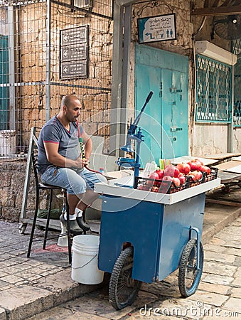 The seller of freshly squeezed juices sits and smokes nargila in anticipation of buyers on the market in the old city of Acre in I Editorial Stock Photo