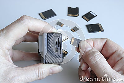 Action camera and microSD memory card in hands on the back of other SD memory cards. Background from gadgets and digital devices Stock Photo