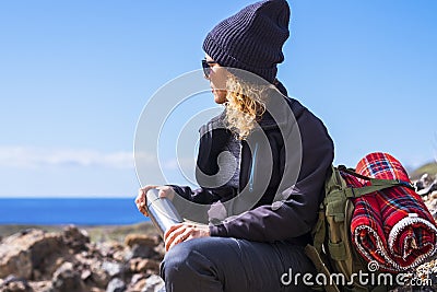 Active adult lady resting and taking a break while do trekking adventure activity inthe nature. Woman sit down on the rocks Stock Photo