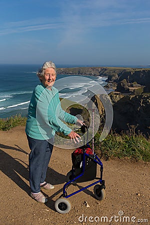 Active elderly lady pensioner in eighties with three wheel mobility frame by beautiful coast scene Stock Photo