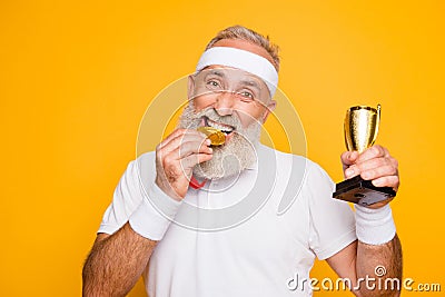 Active emotional cool grandpa holding reward, eating the metal s Stock Photo