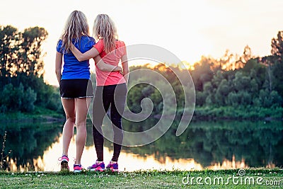 Active family at outdoor. two flexibility blonde woman twin sisters in stylish sportswear enjoy the sunset in the Stock Photo