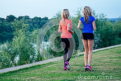 Active family at outdoor. two flexibility blonde woman twin sisters in stylish sportswear an evening jogging walking in Stock Photo
