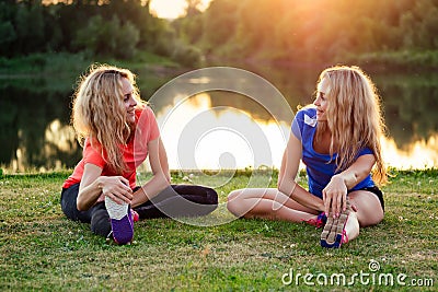 Active family at outdoor. two flexibility curly blonde woman twin sisters in stylish sportswear warm-up stretching full Stock Photo