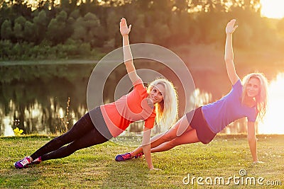 Active family at outdoor. two flexibility curly blonde woman twin sisters in stylish sportswear warm-up yoga muscles in Stock Photo