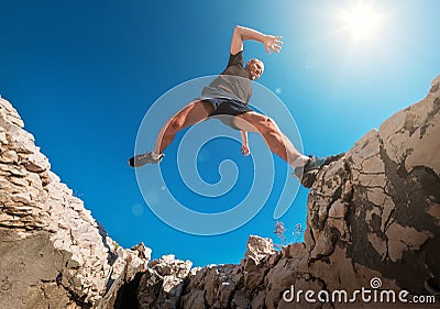 Active fast running mountain sky runner smiling and jumping over the cleft cliff during the morning jogging. Sporty people Stock Photo