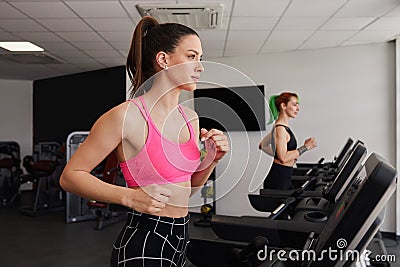 Active fit brunette woman smiling, pink top, running on gym treadmill Stock Photo