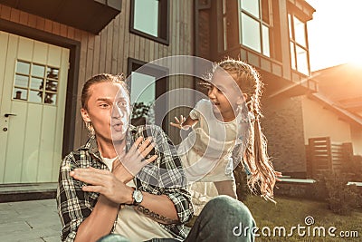 Active good-looking father in checkered shirt having game time with her daughter Stock Photo