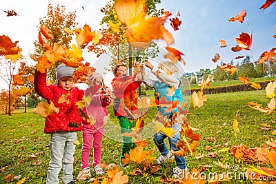 Active group of children play with flying leaves Stock Photo