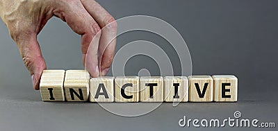 Active or inactive symbol. Businessman turns wooden cubes and changes the word Inactive to Active. Beautiful grey table grey Stock Photo